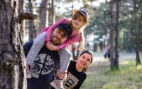 A joyful family enjoying a playful day in a sunlit forest park, capturing the essence of togetherness.
