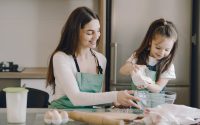 A joyful mother and daughter bonding while baking in the kitchen, smiling and enjoying the activity.